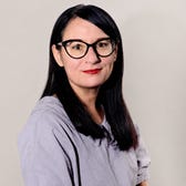 A woman with straight, dark hair wearing cateye glasses