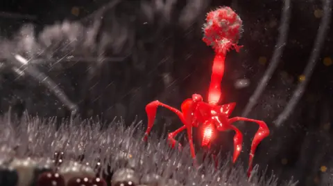 Getty Images This image is a scientific illustration of a bacteriophage. The bacteriophage is shown landing on a grey-hairy surface, with a geometric head, a segmented tail, and multiple thin leg-like structures extending from its base. The virus is rendered in glowing red that stands out from the grey background.