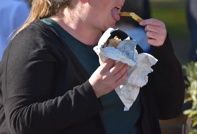 Obese lady eating fast food in the street