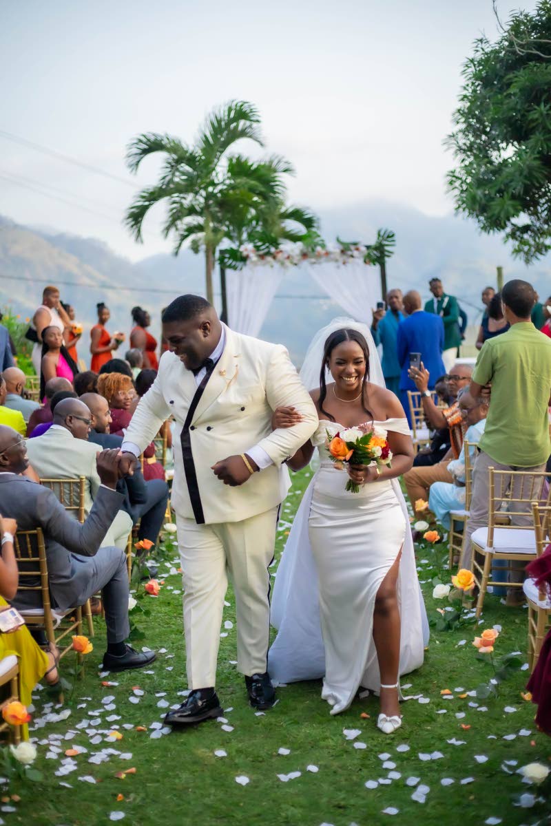 Dexter and Tamalcia happily exit their wedding ceremony as guests celebrate them becoming one.
