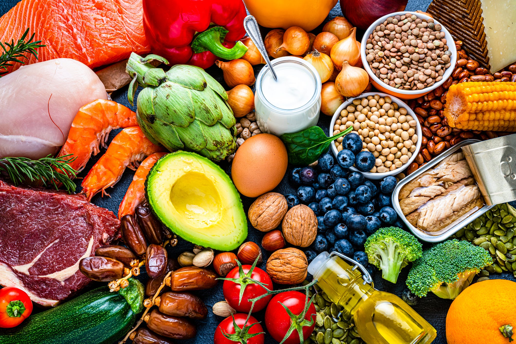 overhead view of a large group of healthy raw food for flexitarian mediterranean diet the composition includes salmon, chicken breast, canned tuna, cow steak, fruits, vegetables, nuts, seeds, dairi products, olive oil, eggs and legumes high resolution 42mp studio digital capture taken with sony a7rii and zeiss batis 40mm f20 cf lens