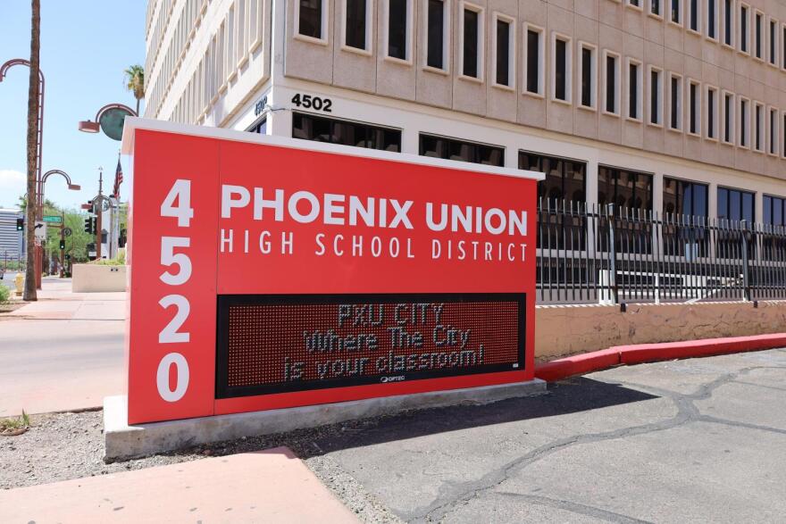Red and white sign with electric screen showing announcements in front of building
