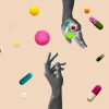 Hands in black and white dropping a collection of pills on a pink background