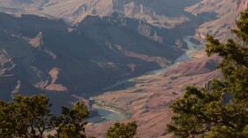 A blue river flows through a large, rocky desert canyon