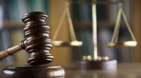 brown wooden gavel in the foreground, out of focus scales of justice in the background