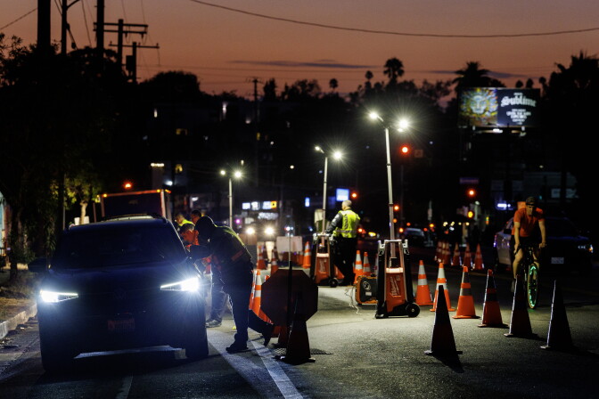 Cars pull up at a DUI checkpoint at night