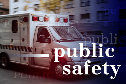 Ambulance driving through an urban setting with the words public safety overlaid in white.