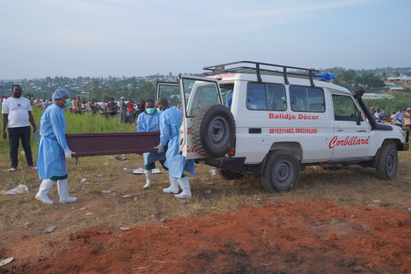 People dressed in protective gear unload a coffin containing the remains of six-year-old Baudjo Baraka Jules, who died of Ebola, for a burial service in Bunia, Ituri province, eastern Congo, Tuesday, Aug. 18, 2026. (AP Photo/Dieudonne Dirole)