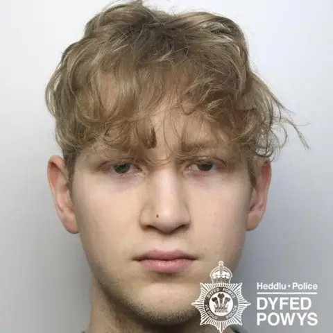 Dyfed-Powys Police A young man is pictured with blonde hair looking at the camera