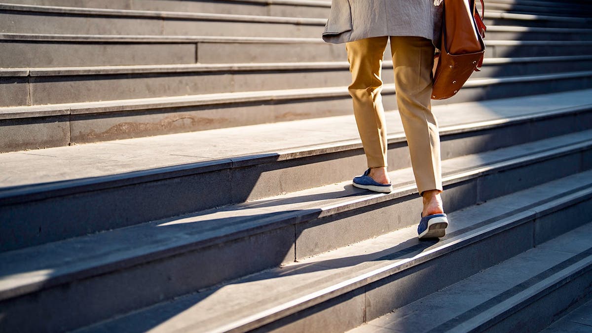 A woman walks up stairs outside.