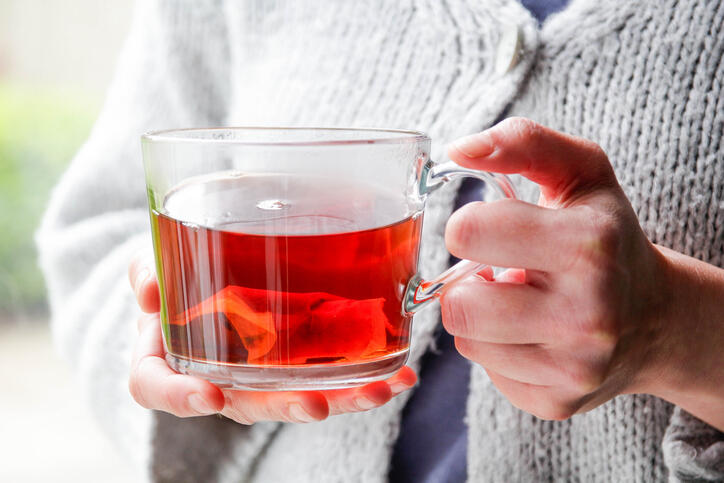 A person holding a mug of tea with a tea bag in it