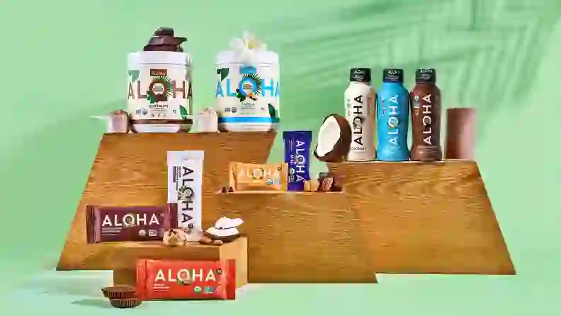 ALOHA protein powders, bars, and drinks displayed on wood risers