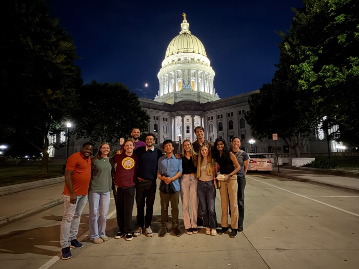 photo of a group of researchers standing in front of a lit domed building at night