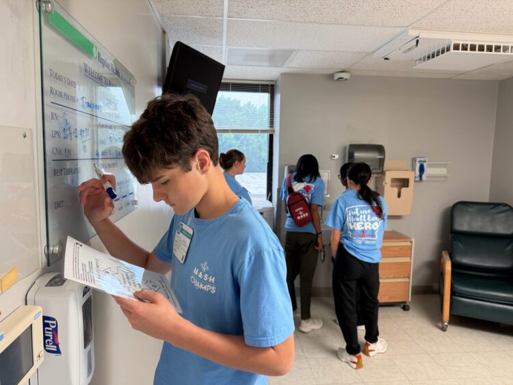 A camper writes on a patient chart at the Malvern MASH Camp.