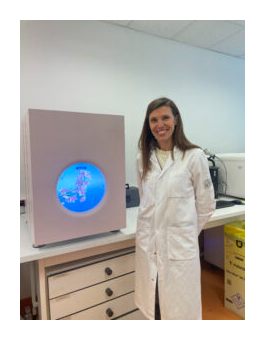 Claire Guissart standing beside a PacBio Vega system in the laboratory.