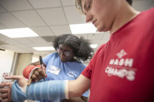 Simariah Pearson signs the cast for Nathan Taylor, a former MASH camper from White Hall who now attends the UAMS College of Medicine.