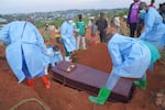 People dressed in protective gear lower into a grave the coffin containing the remains of 6-year-old Baudjo Baraka Jules, who died of Ebola, in Bunia, Ituri province, eastern Congo, Tuesday, Aug. 18, 2026.