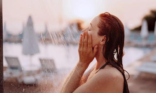 Person rinsing off in outdoor shower after swimming