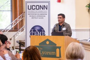 A researcher presenting at a lectern with the "UConn INCHIP" logo behind him