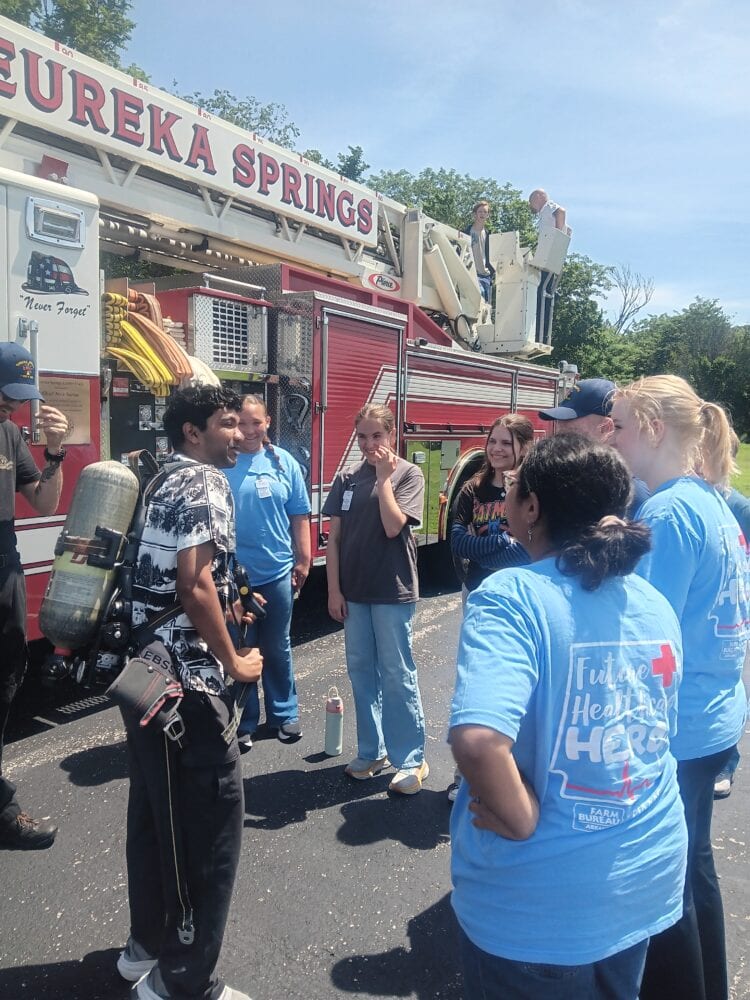 Male MASH student tries on air tanks at Eureka Springs firefighter demonstration