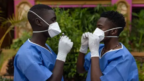 Getty Images Two men wearing protective gear face each other while adjusting their masks