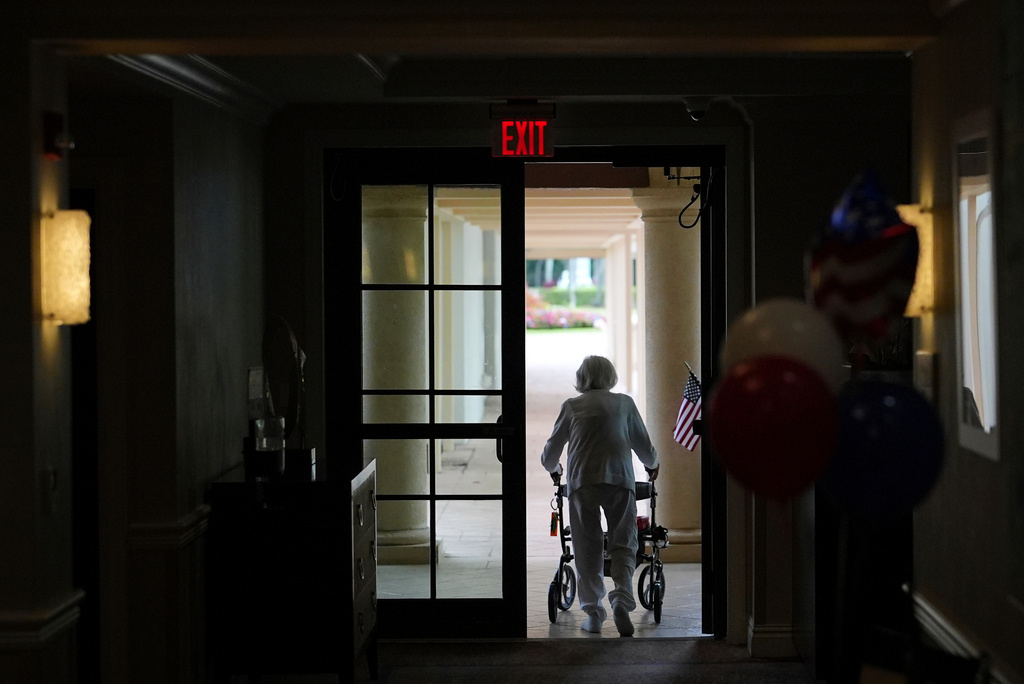 A woman uses a walker as she exits an assisted living building, July 4, 2025, in Boca Raton, Fla.