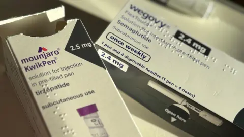 Two boxes containing pre-filled injection pens. On the left a white card box with purple writing is labelled as containing a Mounjaro Kwikpen marked for "subcutaneous use". On the right of the picture is another white box with black detailing labelled as Wegovy states it's a pre-filled pen containing Semaglutide.