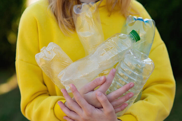 Person holding an armful of empty plastic water bottles.