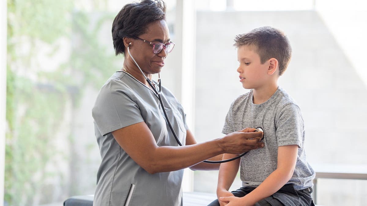 A doctor listens to a child's heart.