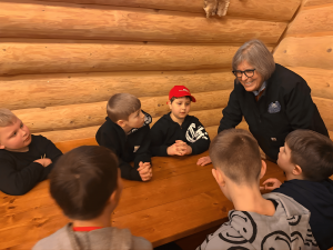 Woman Susan Mathison leans over to speak with children at a table.