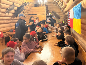 Children at a table wave to American visitors.