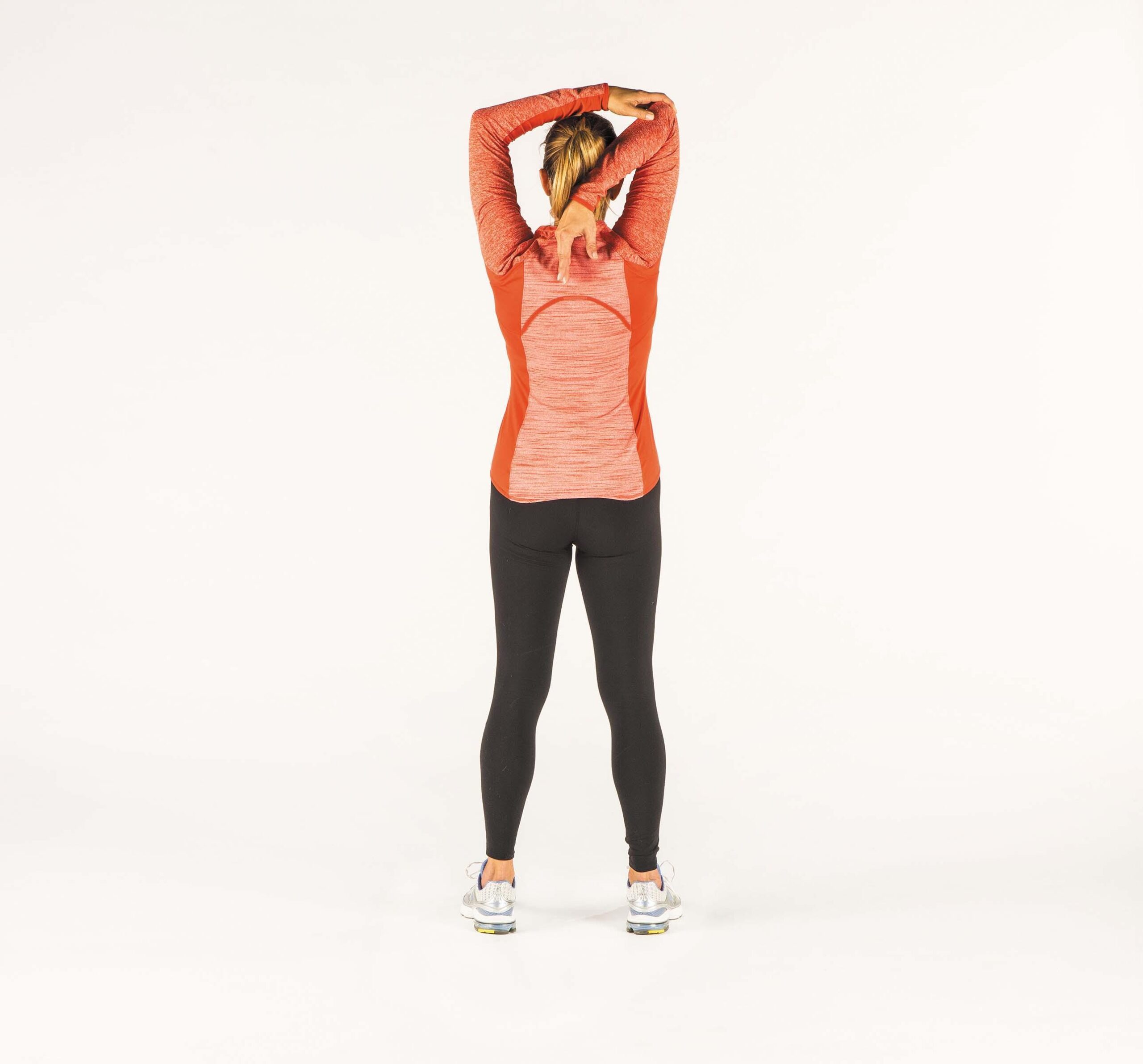 A woman demonstrates how to perform the triceps stretch exercise as described in the article.