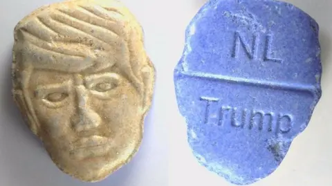 Trimbos Institute Composite pictures of two versions of the same pill. At the top is the front and back picture of an ecstasy pill in the shape of US President Donald Trump's head. The green front is a depiction of Trump's face carved into the pill; the back, in red, features the word "NL" carved at the top of a break line under which is stamped the word "Trump".
At the bottom of the image is the same pill but in yellow and blue