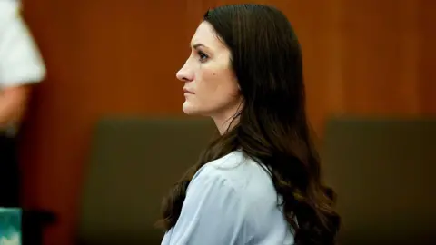 Getty Images Lindsay Clancy in court. Long brown hair hangs down her back as she sits wearing a pale blue shirt.