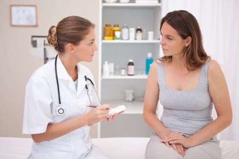Doctor explaining medication to patient in a clinic exam room.