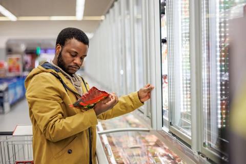Person looking over bag of frozen veggies in grocery store