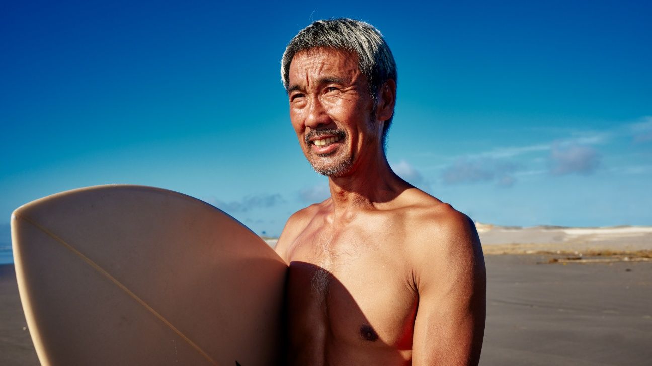 Older male with surfboard at beach