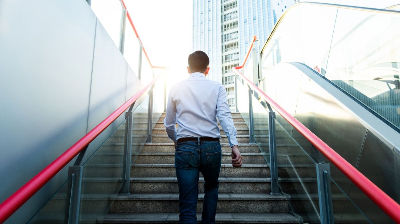 Mail climbing stairs outside in a city instead of taking the escalator