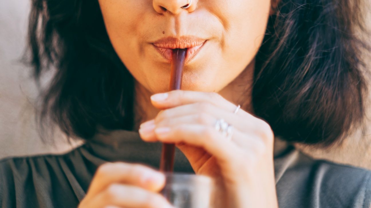 Close up of female drinking soda through a straw