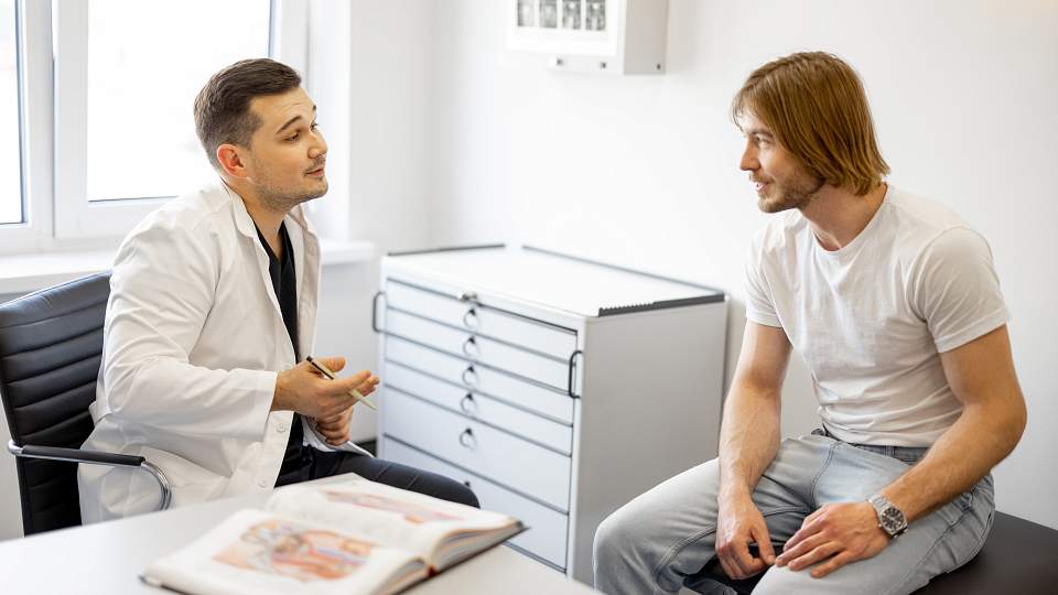 Male Patient and Doctor sit in a clinic room