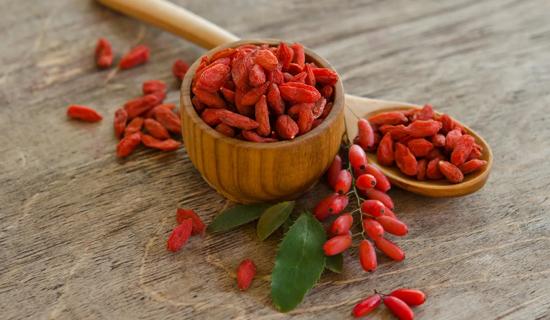 Dried and fresh goji berries in wooden bowl and spoon