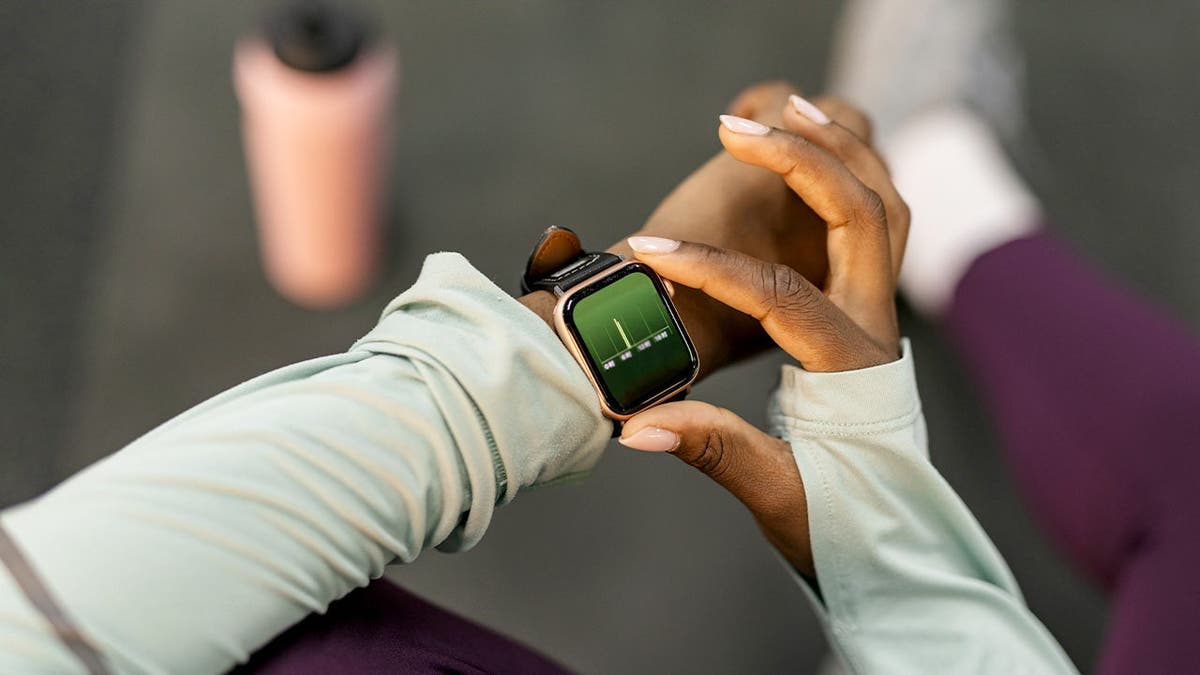 A woman checks her heart rate on a wrist monitor.