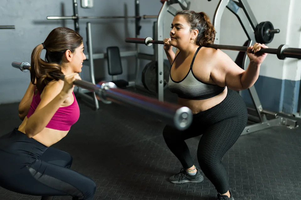 Women performing barbell strength training exercises in a gym, reflecting the shift toward foundational fitness in 2026.