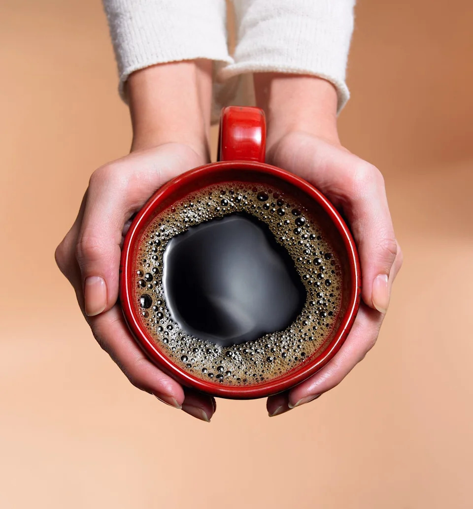 "Woman holding coffee cup, close-up, overhead view"