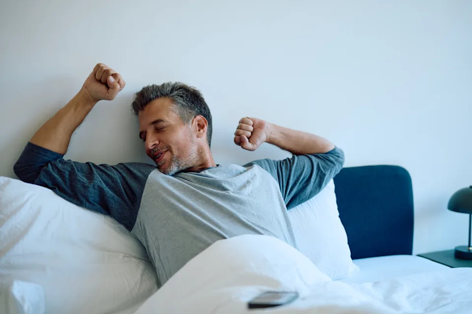 Man stretching in bed after a full night of sleep, highlighting the connection between sleep quality and heart health