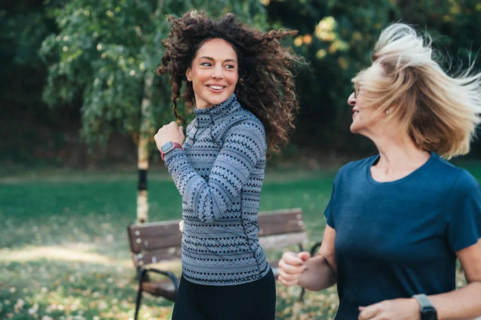 Two women jogging together in a park as part of a sustainable exercise routine for heart health