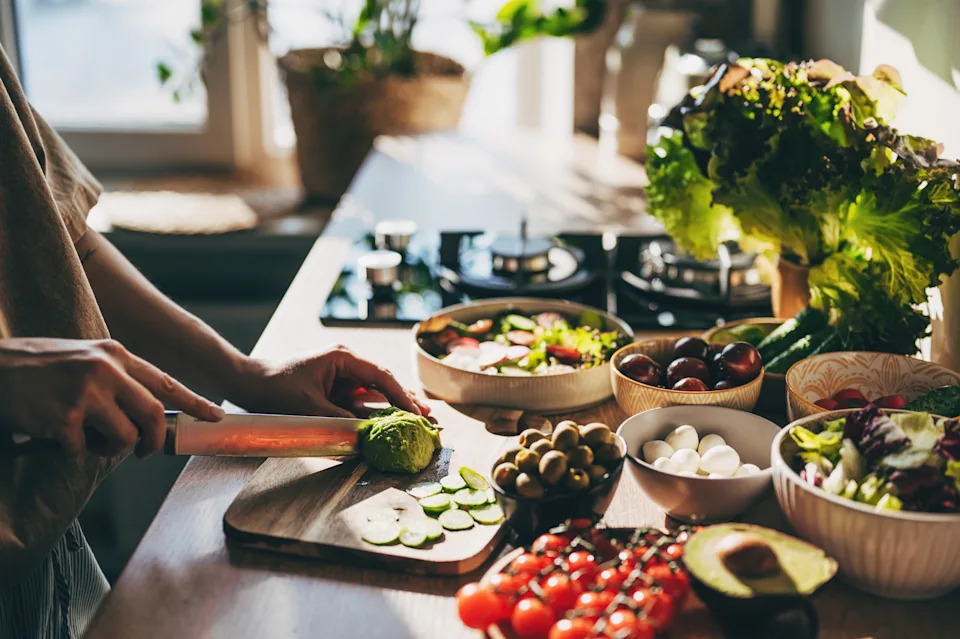 Healthy dinner or lunch. Woman in t-shirt and jeans eating vegan super bowl or Buddha bowl with hummus, vegetable, salad, beans, couscous and avocado
