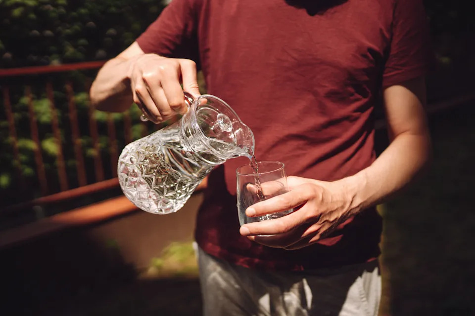 Person pouring drinking water into a glass.