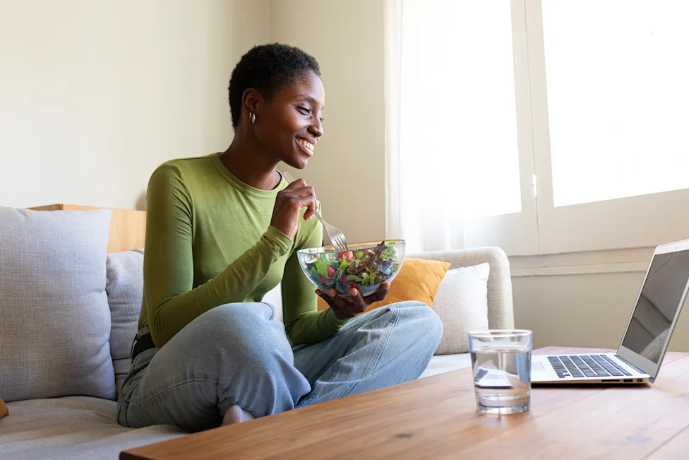 Woman eating salad while working from home