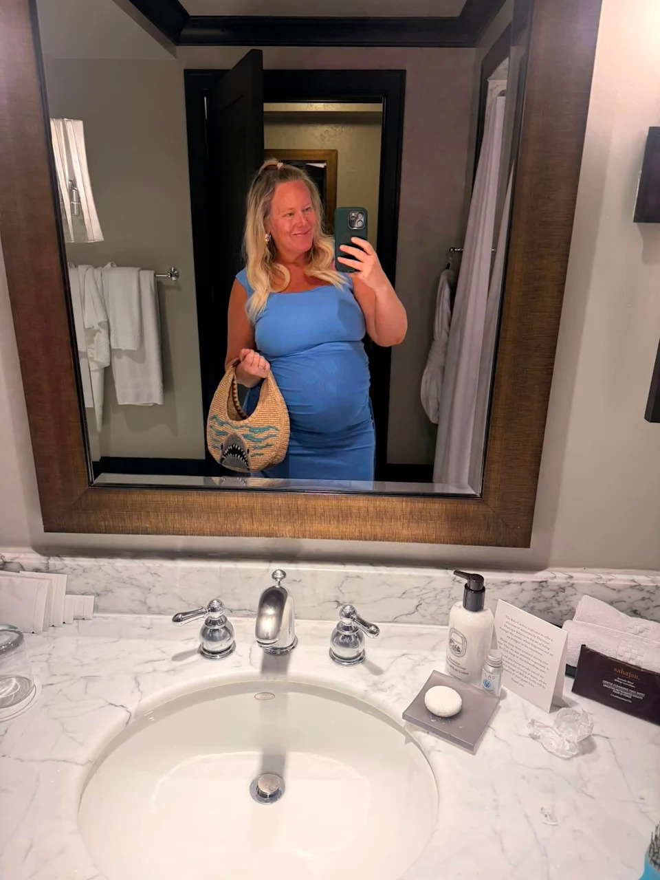 Brittany Anas takes a mirror selfie at eight months pregnant while wearing a fitted blue dress.